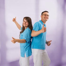 zwei lächelnde Pflegekräfte stehen Rücken an Rücken