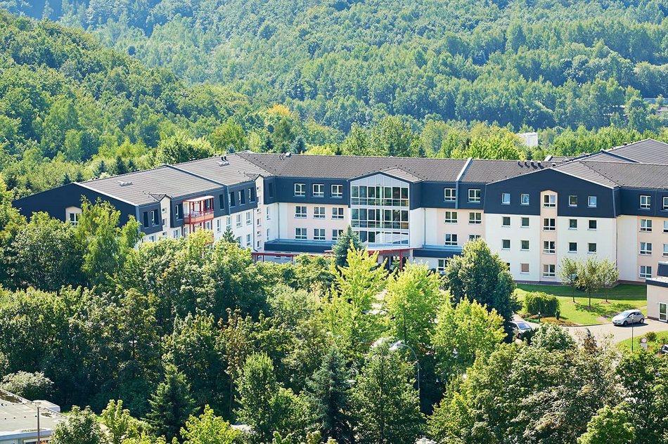 Großes Gebäude umgeben von Bäumen und grüner Landschaft