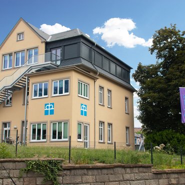 Modernes Diakonie-Gebäude mit Fahnen und blauem Himmel im Hintergrund