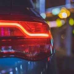 Rücklicht eines Autos bei Nacht mit Stadtlichtern im Hintergrund