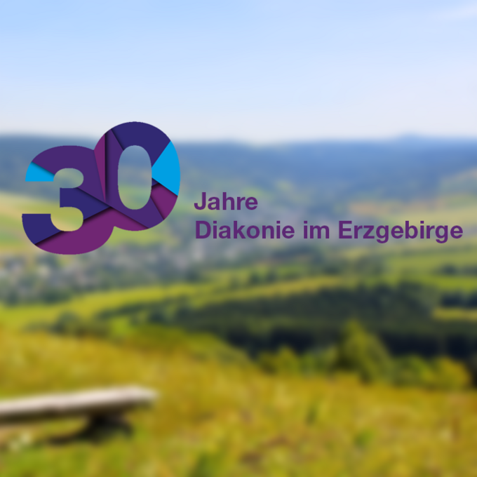 im Vordergrund des Bildes steht der Text "30 Jahre Diakonie im Erzgebirge", im Hintergrund sieht man verschwommen eine erzgebirgische Landschaft mit Bergen und Wäldern.