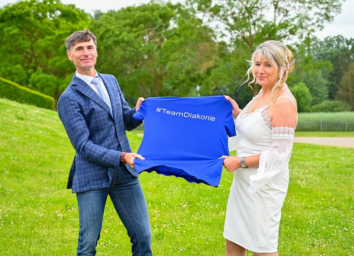 Mann und Frau halten gemeinsam blaues Shirt mit Schriftzug „#TeamDiakonie“