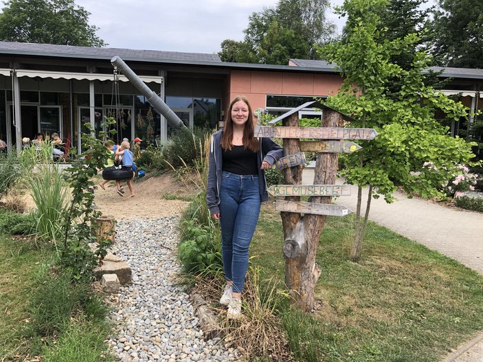 Frau steht lächelnd im Garten vor Gebäude mit Solardach