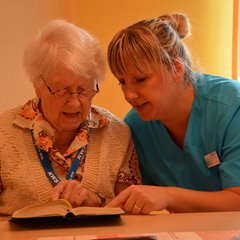 Senioren und Pflegerin lesen gemeinsame 