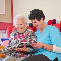 Senioren und Pflegerin am Lesen 